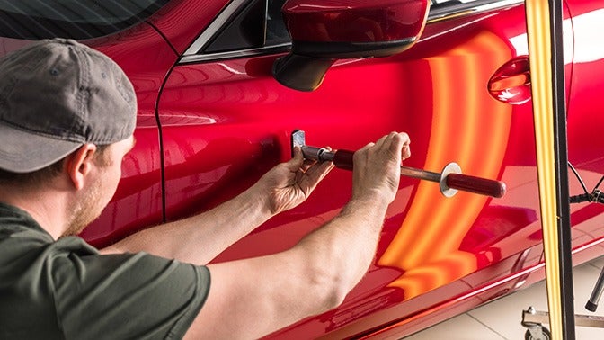 image of a man removing a dent from a car