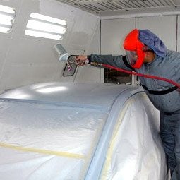 service tech painting car in shop