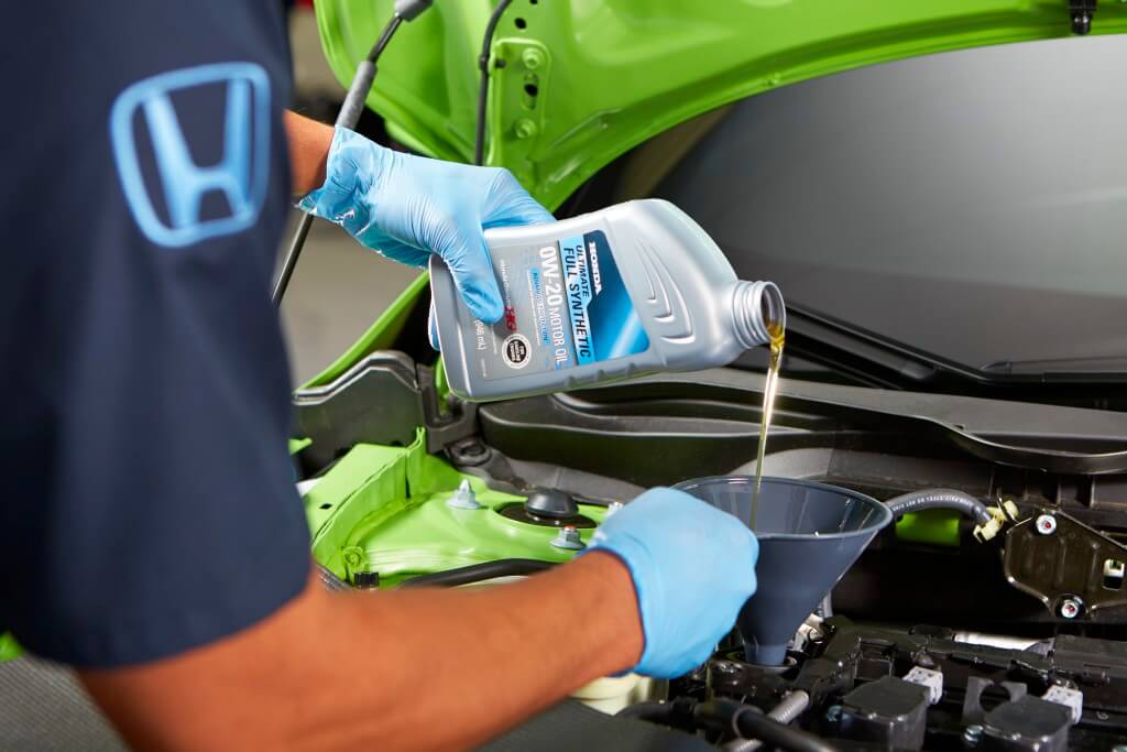 image of a Honda technician pouring oil into an engine
