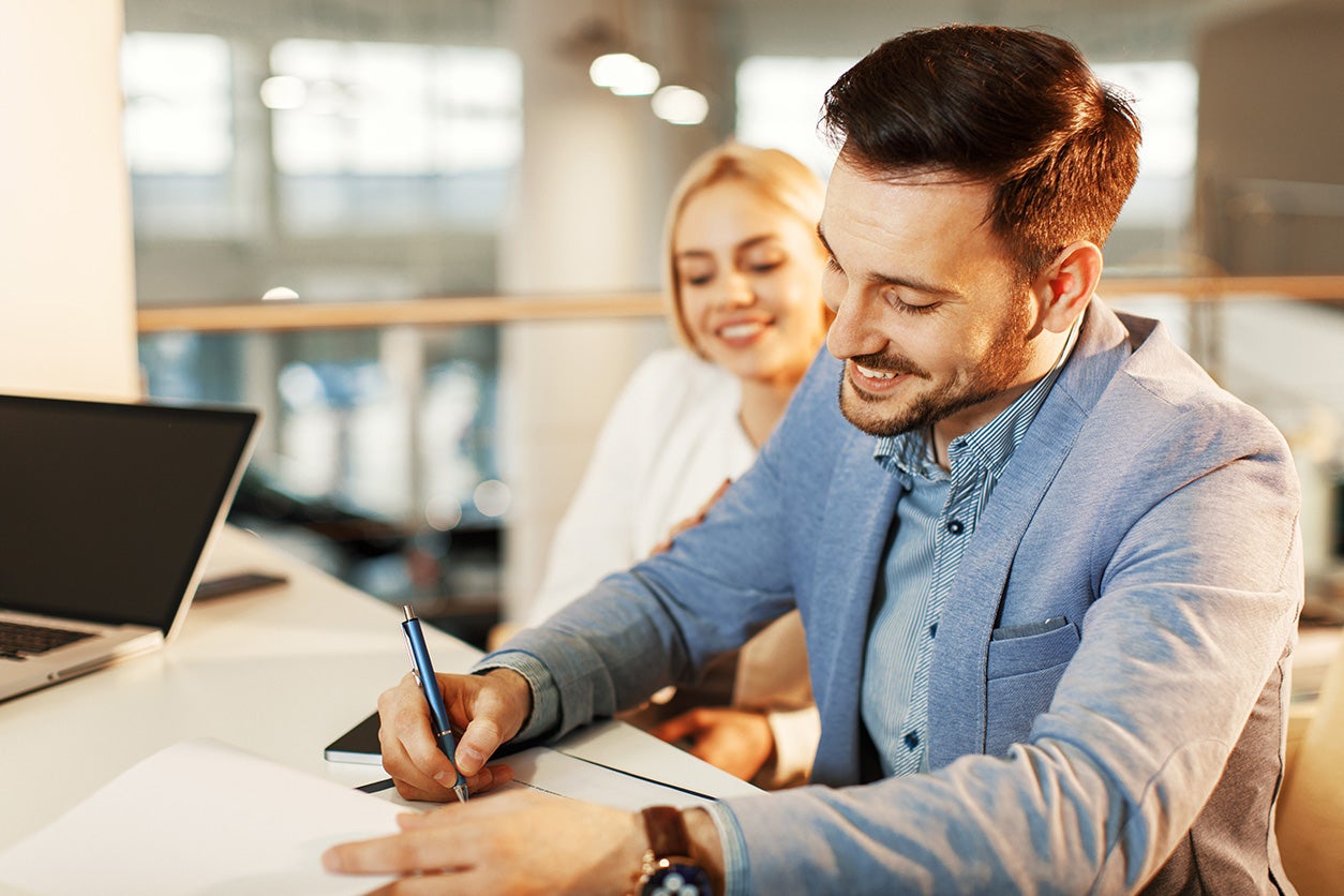 image of a man smiling and signing paperwork